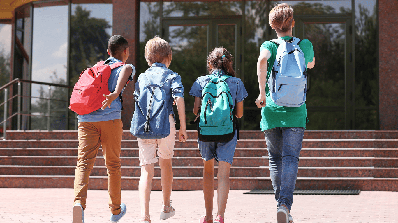 Grupo de chicos y chicas adolescentes con mochilas escolares entrando al instituto